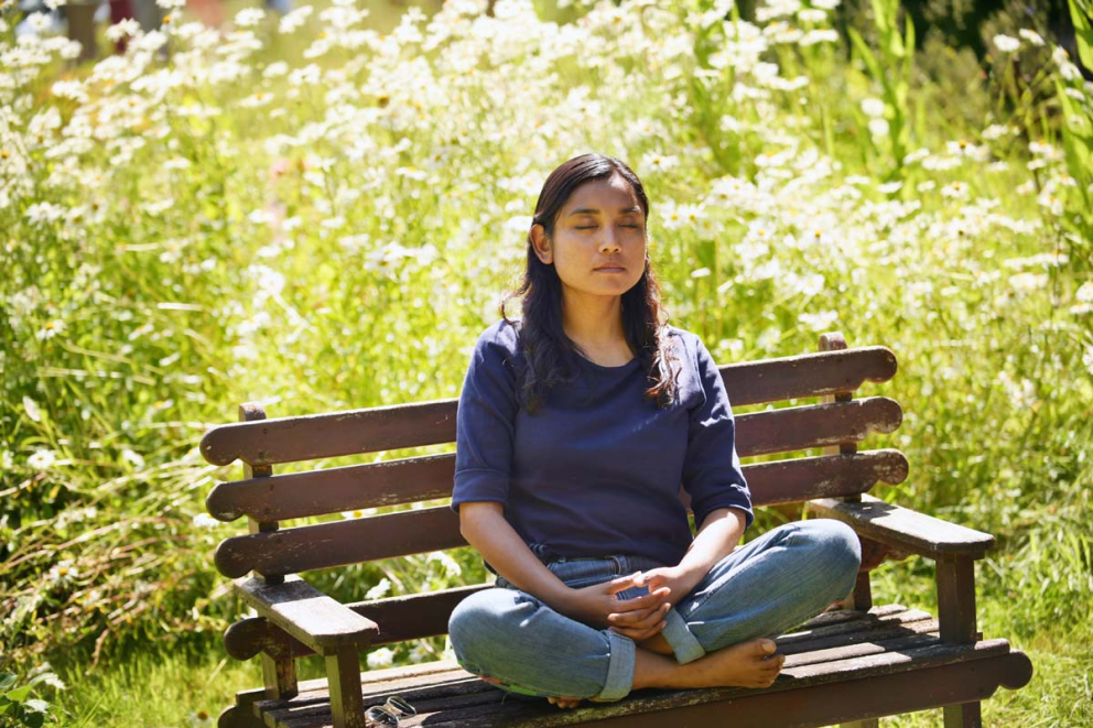 A person meditates on a bench at The Barn at The Sharpham Trust mindfulness retreat centre